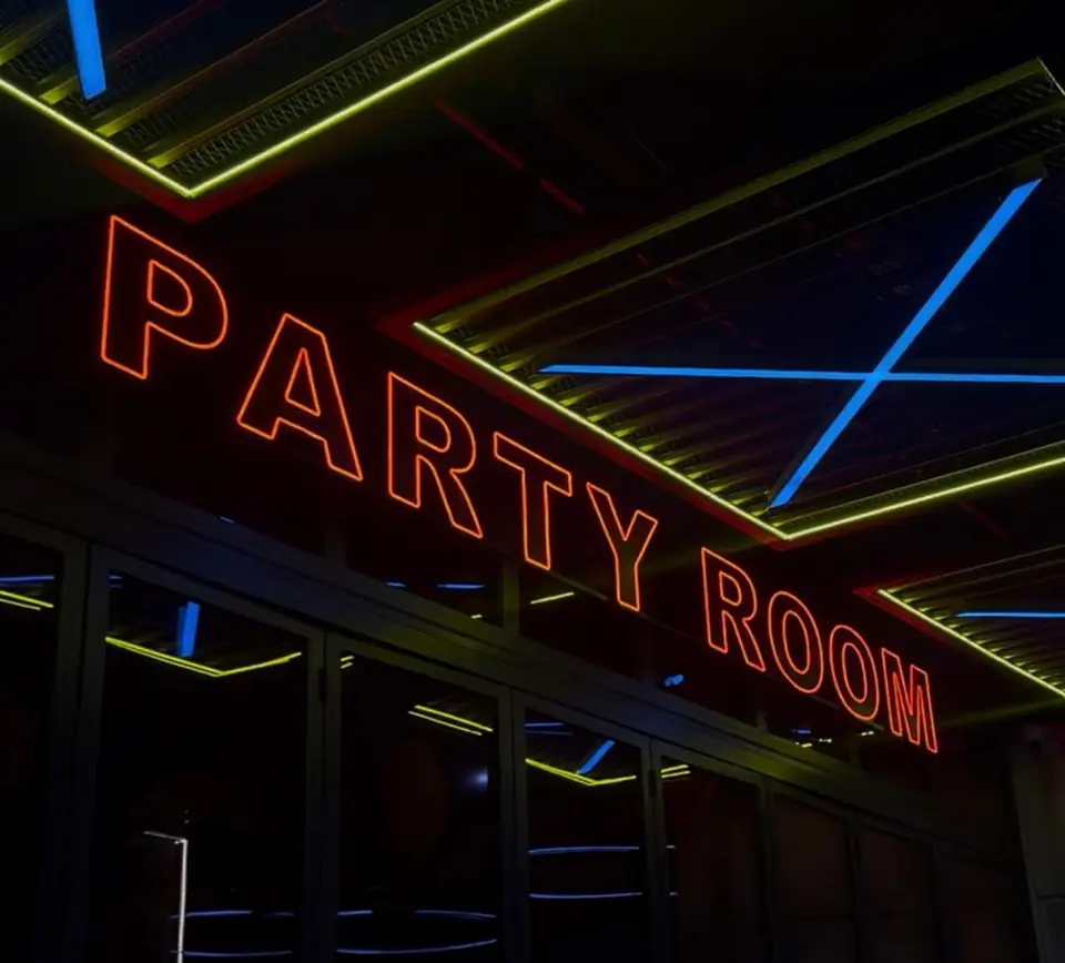 Orange LED neon Party Room sign under lit ceiling frames