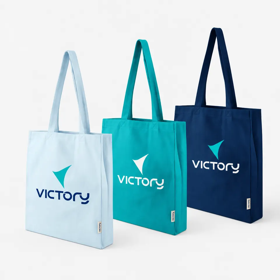 Three branded canvas tote bags in light blue, teal and navy